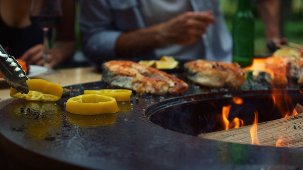 Nicht erkennbarer Mann, der draußen kocht Koch, der Zwiebel und Paprika auf den Grill legt