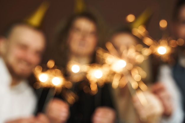 Nicht fokussiertes Bild von Partyleuten mit brennenden Wunderkerzen, die Feiertag oder Ereignis feiern