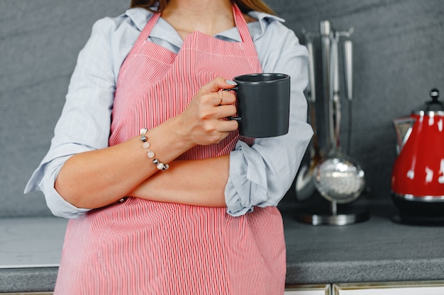 Nicht wiedererkennbare Frau, die eine Tasse Kaffee hält, während sie oben in der Küche steht