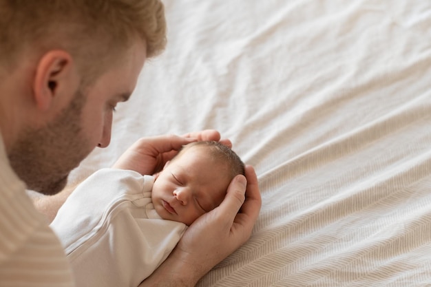 Foto nicht wiederzuerkennender mann, vater, der kind hält, kaukasischer, behaarter, brünettes, süßes neugeborenes baby, das ein oder zwei personen schläft