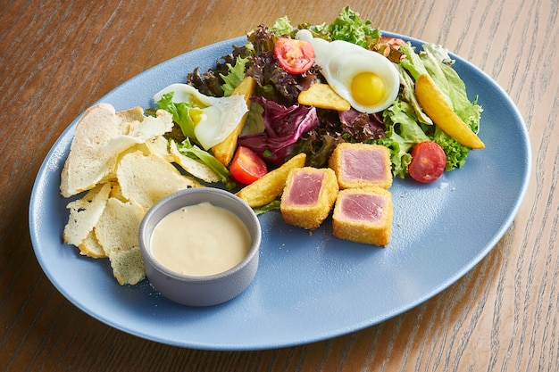 Nicoise-Salat mit frischen Tomaten, Spargel, Chilischoten, Oliven, Wachteleiern und gebratenem Thunfisch.