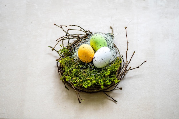 Nido con huevos de Pascua de colores aislado sobre un fondo de piedra gris decoraciones de pascua closeup