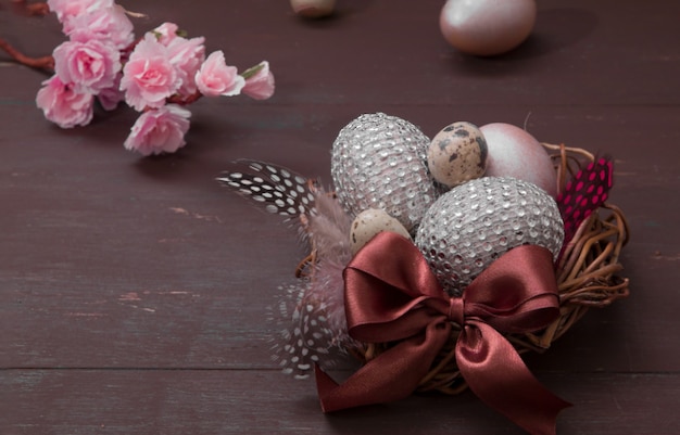 Nido de Pascua feliz con huevos sobre un fondo de madera. Tarjeta de felicitación de Pascua feliz con huevos de Pascua creativos y flores en flor