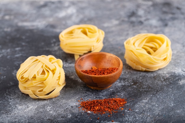 Nidos de pasta cruda con pimienta molida colocados sobre una mesa de mármol.