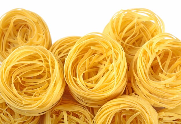 Nidos de tallarines de pasta italiana cruda sobre un blanco