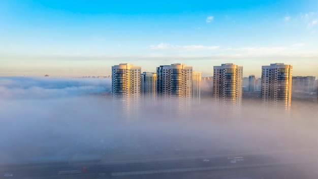 La niebla de la mañana de otoño que se arrastra hacia la ciudad, las cimas de los edificios de gran altura parecen niebla