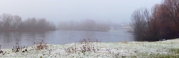 Niebla sobre el río y la orilla del río cubierto de nieve en invierno, árboles en la orilla del río