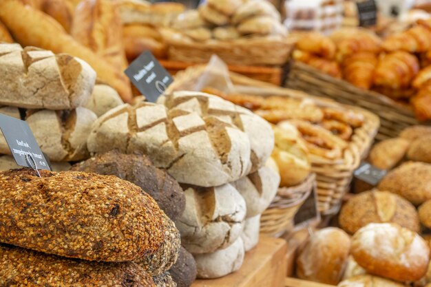 Niederlande. Bauernmarkt in Amsterdam. Viele Arten von Brot und Croissants. Das Schild im Vordergrund lautet "Knoblauch, sonnengetrocknete Tomate" auf Niederländisch