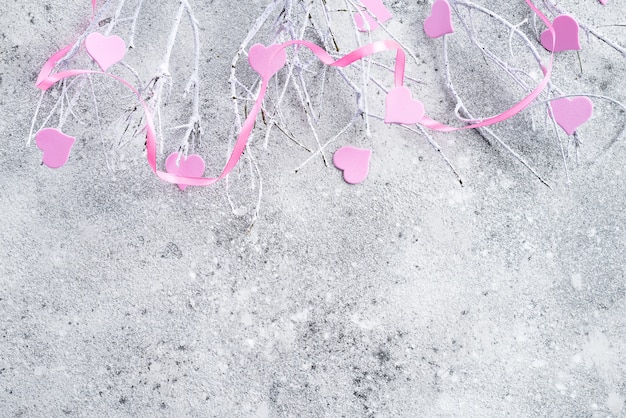 Niederlassungen im Schnee mit rosa Herzen auf einem konkreten Hintergrund