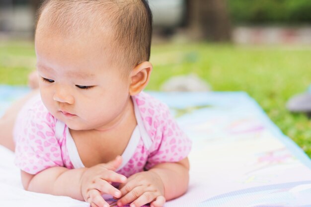 niedliche asiatische Babylüge anfällig auf dem Boden am Park