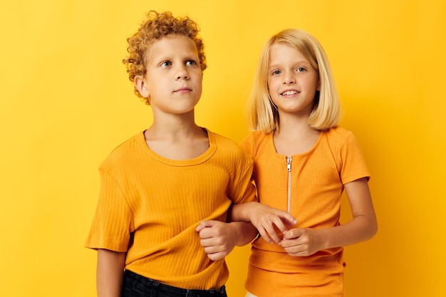 Niedliche, stilvolle Kinder in gelben T-Shirts, die nebeneinander stehen, Kindheitsgefühle, isolierter Hintergrund