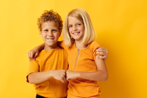 Niedliche, stilvolle Kinder in gelben T-Shirts, die nebeneinander stehen, Kindheitsgefühle, isolierter Hintergrund