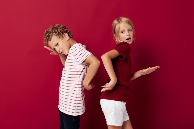 Niedliche Vorschulkinder stehen nebeneinander auf rotem Hintergrund der Alltagskleidung