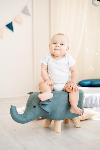 Niedlicher kleiner Junge in einem hellen Kinderzimmer mit einem Wigwam, der in einem Baumwollbody spielt und lächelt