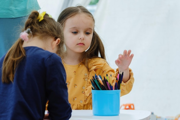 Niedliches europäisches Mädchen, das mit Buntstift malt. Bildungskonzept für Kindergartenkinder