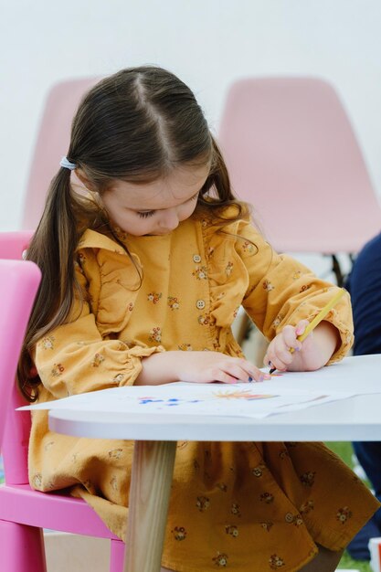 Niedliches europäisches Mädchen, das mit Buntstift malt. Bildungskonzept für Kindergartenkinder