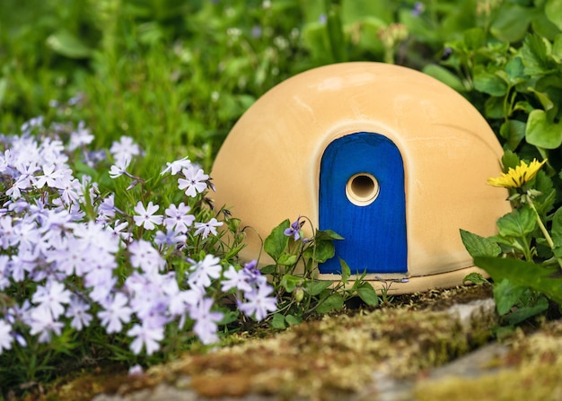 Niedliches Keramikhaus mit attraktiver blauer Tür zum Nisten von Hummeln in einem Frühlingsgarten