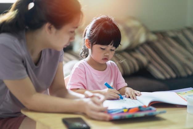 Niedliches kleines Kind, das mit bunten Farben malt Asiatisches Mädchen und ihre Mutter mit Buntstiftzeichnung colorBaby-Künstleraktivität Lifestyle-Konzept