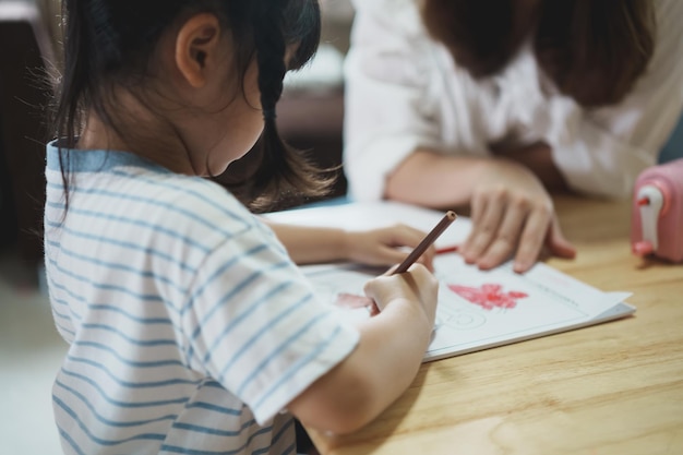 Niedliches kleines Kind, das mit bunten Farben malt Asiatisches Mädchen und Mutter mit Buntstift-Zeichnungsfarbe Tochter und Mutter machen Hausaufgaben, die Zeichentrickfiguren färben Baby-Künstler-Aktivitäts-Lifestyle-Konzept