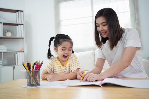 Niedliches kleines Kind, das mit bunten Farben malt Asiatisches Mädchen und Mutter mit Buntstift-Zeichnungsfarbe Tochter und Mutter machen Hausaufgaben, die Zeichentrickfiguren färben Baby-Künstler-Aktivitäts-Lifestyle-Konzept