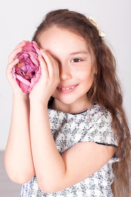 Niedliches kleines Mädchen mit einem Strauß rosa Rosen isoliert auf einem grauen Studiohintergrund in voller Wachstumsfrühlingszeit