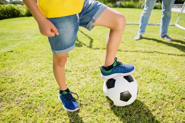 Foto niedriger abschnitt des jungen mit bein auf fußball