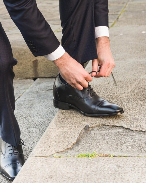 Foto niedriger teil des mannes steht auf der straße und schnürt seine schuhe