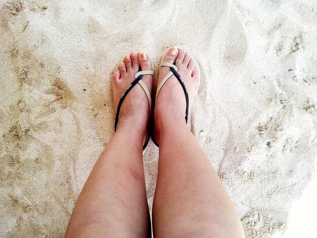 Foto niedriger teil einer frau, die am sandstrand steht