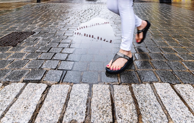 Niedriger Teil einer Frau, die während der Regenzeit auf einem Fußweg geht