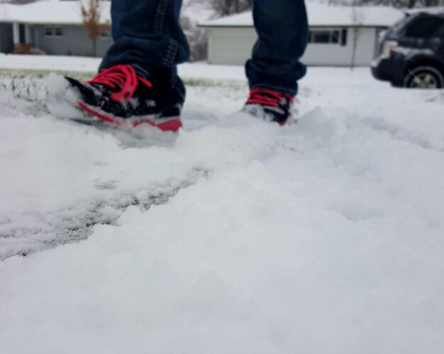 Foto niedriger teil einer person, die auf einem schneebedeckten feld geht