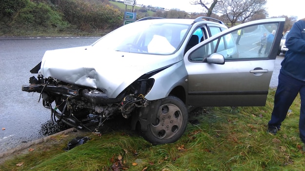 Niedriger Teil eines Mannes, der an einem beschädigten Auto auf der Straße steht