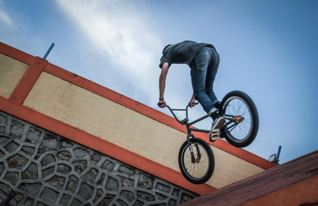 Foto niedriger teil eines mannes, der auf einem fahrrad gegen den blauen himmel ein stunt ausführt