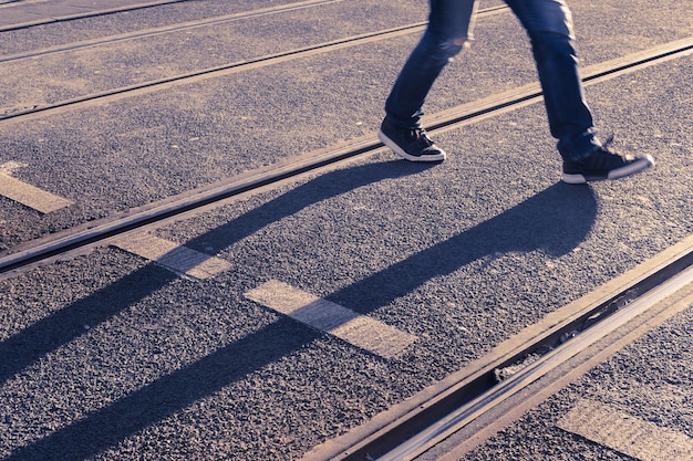 Niedriger Teil eines Mannes, der auf Eisenbahnschienen geht