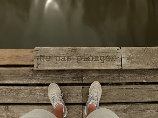 Foto niedriger teil eines mannes, der mit einem text auf dem pier steht