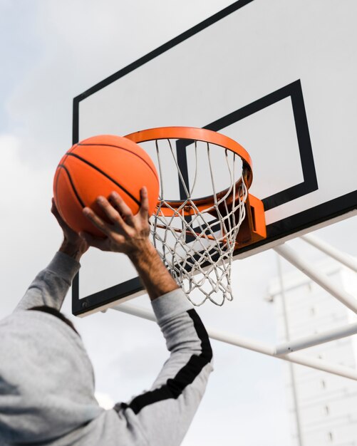 Niedriger Winkel des Jungen, der in Basketballkorb wirft