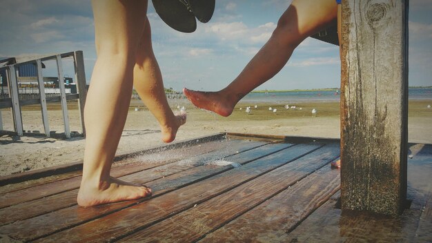 Foto niedrigste gruppe von menschen, die sich in der dusche am strand die beine waschen