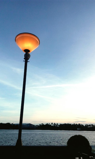 Foto niedrigwinkelansicht der beleuchteten straßenbeleuchtung am see gegen den himmel