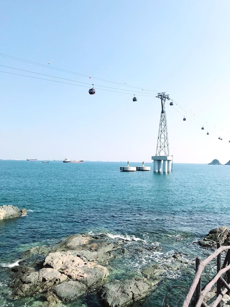 Niedrigwinkelansicht der Seilbahn über dem Meer gegen klaren Himmel