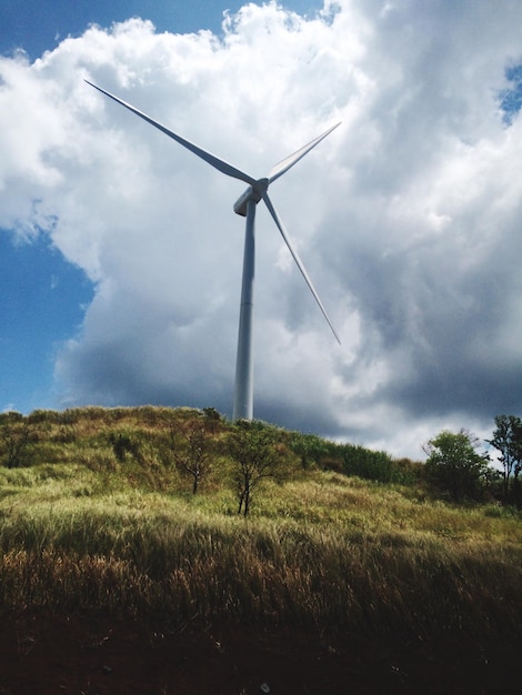 Niedrigwinkelansicht der Windmühle auf einem grasbewachsenen Hügel gegen den Himmel