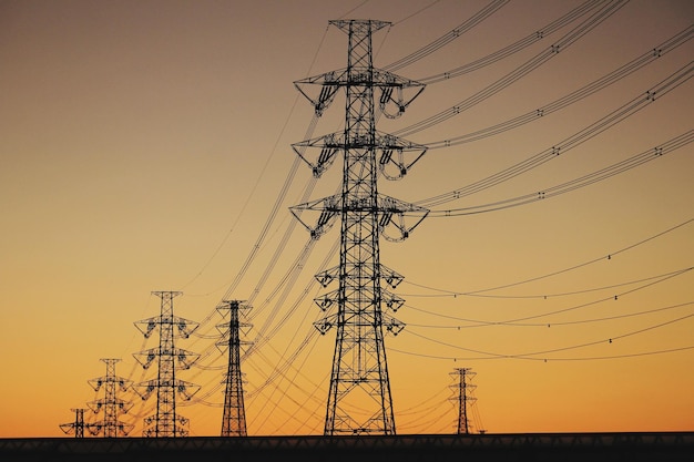 Niedrigwinkelansicht des Silhouette-Elektrizitätspylons gegen den Himmel während des Sonnenuntergangs.