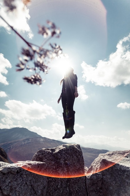 Niedrigwinkelansicht einer Frau, die auf einem Felsen gegen den Himmel schwebt