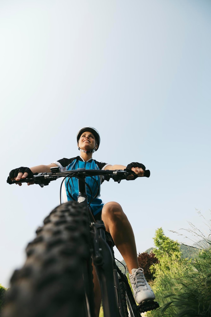 Foto niedrigwinkelansicht einer frau, die gegen einen klaren himmel fahrrad fährt