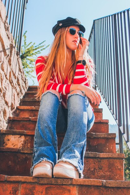 Foto niedrigwinkelansicht einer jungen frau, die auf einer treppe sitzt