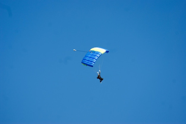 Foto niedrigwinkelansicht einer paragliding-person vor einem klaren blauen himmel