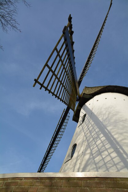 Foto niedrigwinkelansicht einer traditionellen windmühle von einem nackten baum gegen den himmel