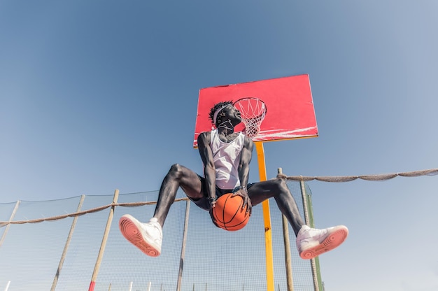 Niedrigwinkelansicht eines Basketballspielers, der gegen einen klaren Himmel springt