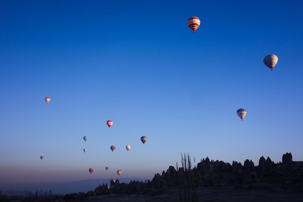 Niedrigwinkelansicht eines Heißluftballons, der bei Sonnenuntergang gegen einen klaren blauen Himmel fliegt