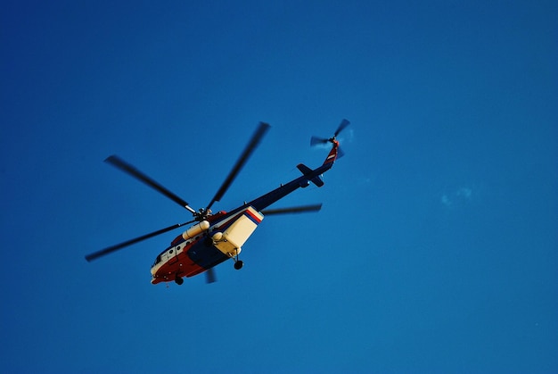 Niedrigwinkelansicht eines Hubschraubers, der gegen den blauen Himmel fliegt