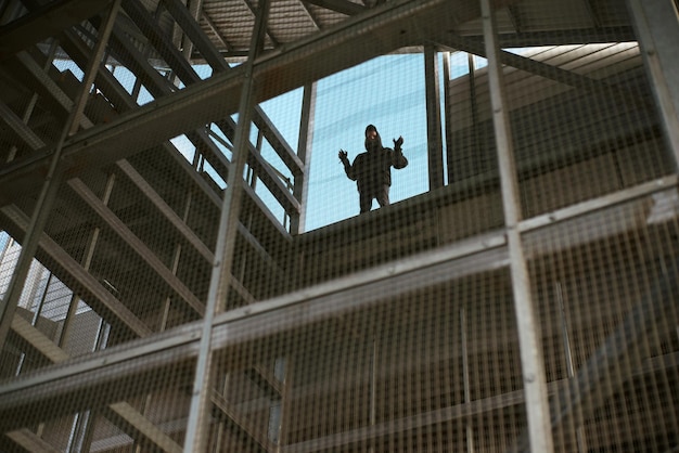 Foto niedrigwinkelansicht eines mannes, der am fenster steht und durch einen zaun gesehen wird