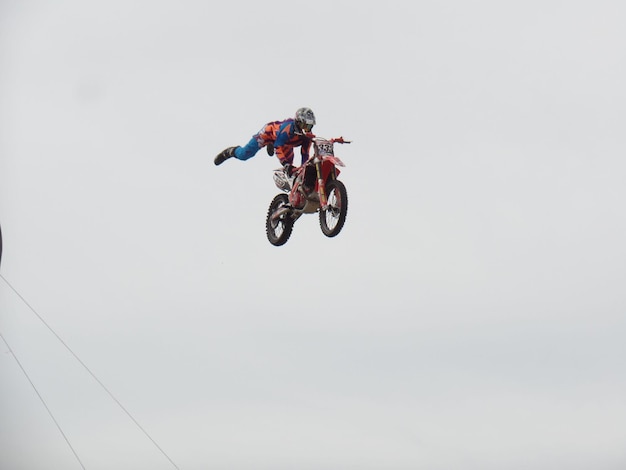 Niedrigwinkelansicht eines Motocross-Bikers in der Luft gegen einen klaren Himmel